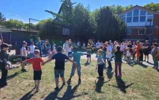 Kinder stehen auf einem Schulgelände und halten sich an den Händen.